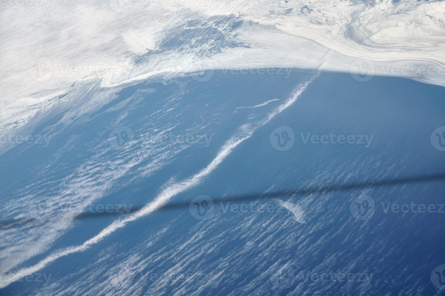 Aerial view from airplane window over clouds to frozen sea with north steam gas pipeline underwater photo