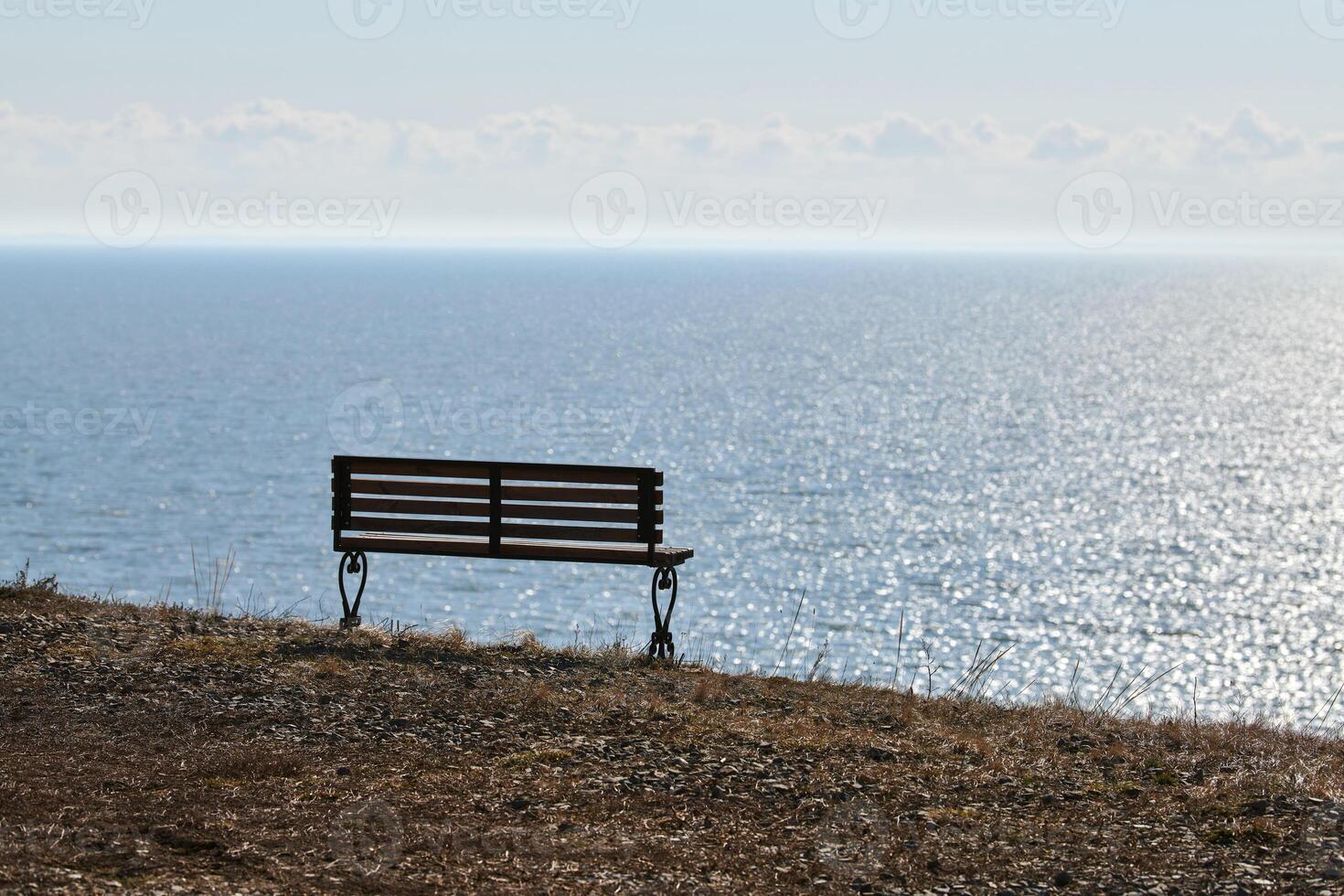 Empty bench on cliff before sea background, peaceful and quiet place for thinking alone photo