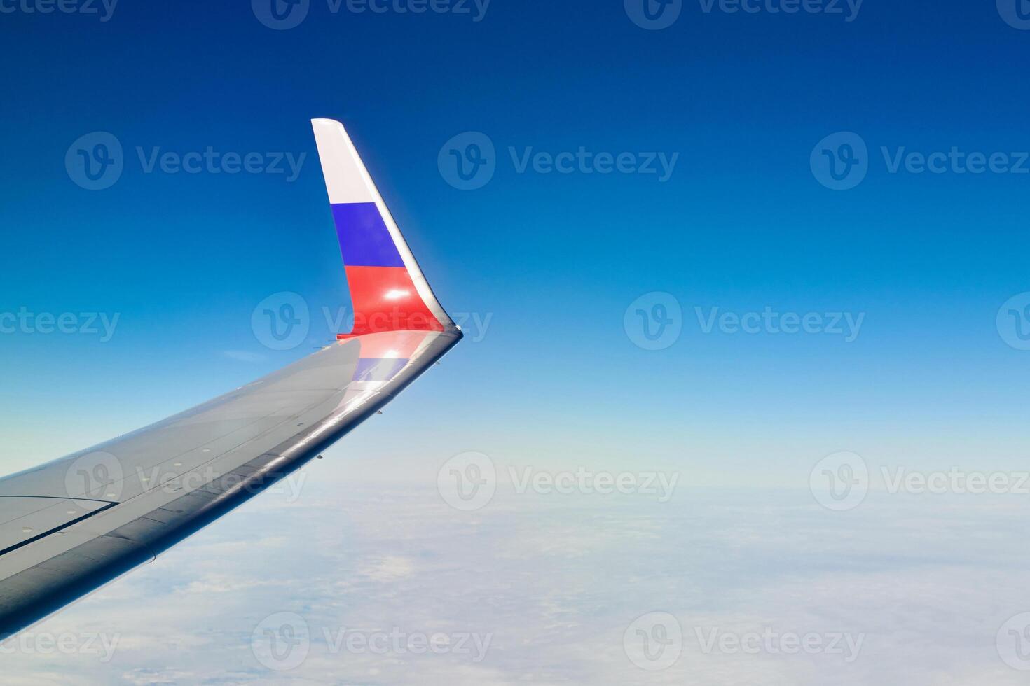 Airplane wing with Russian flag colors over clouds aerial view from aircraft window, parts problem photo