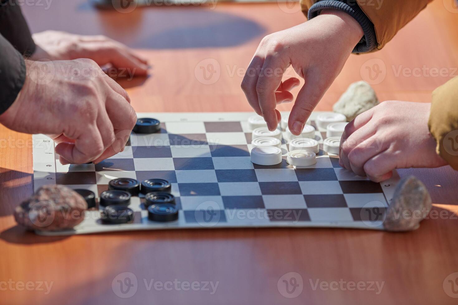 Outdoor draughts competition on paper checkerboard on table, close up players hands photo