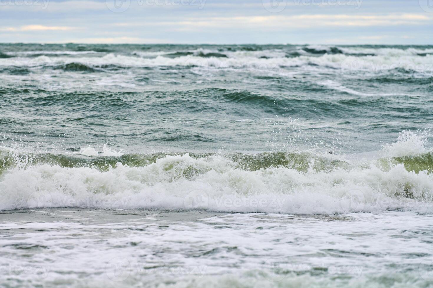 Blue sea with foaming waves and cloudy sky, seascape photo