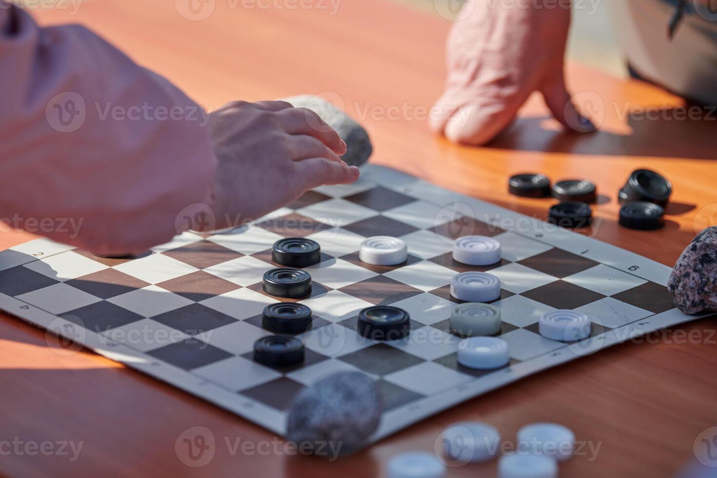 Outdoor draughts competition on paper checkerboard on table, close up players hands photo