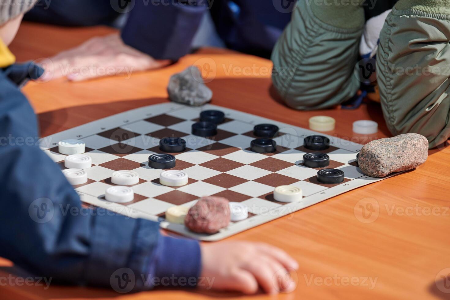 Outdoor draughts competition on paper checkerboard on table, close up players hands photo