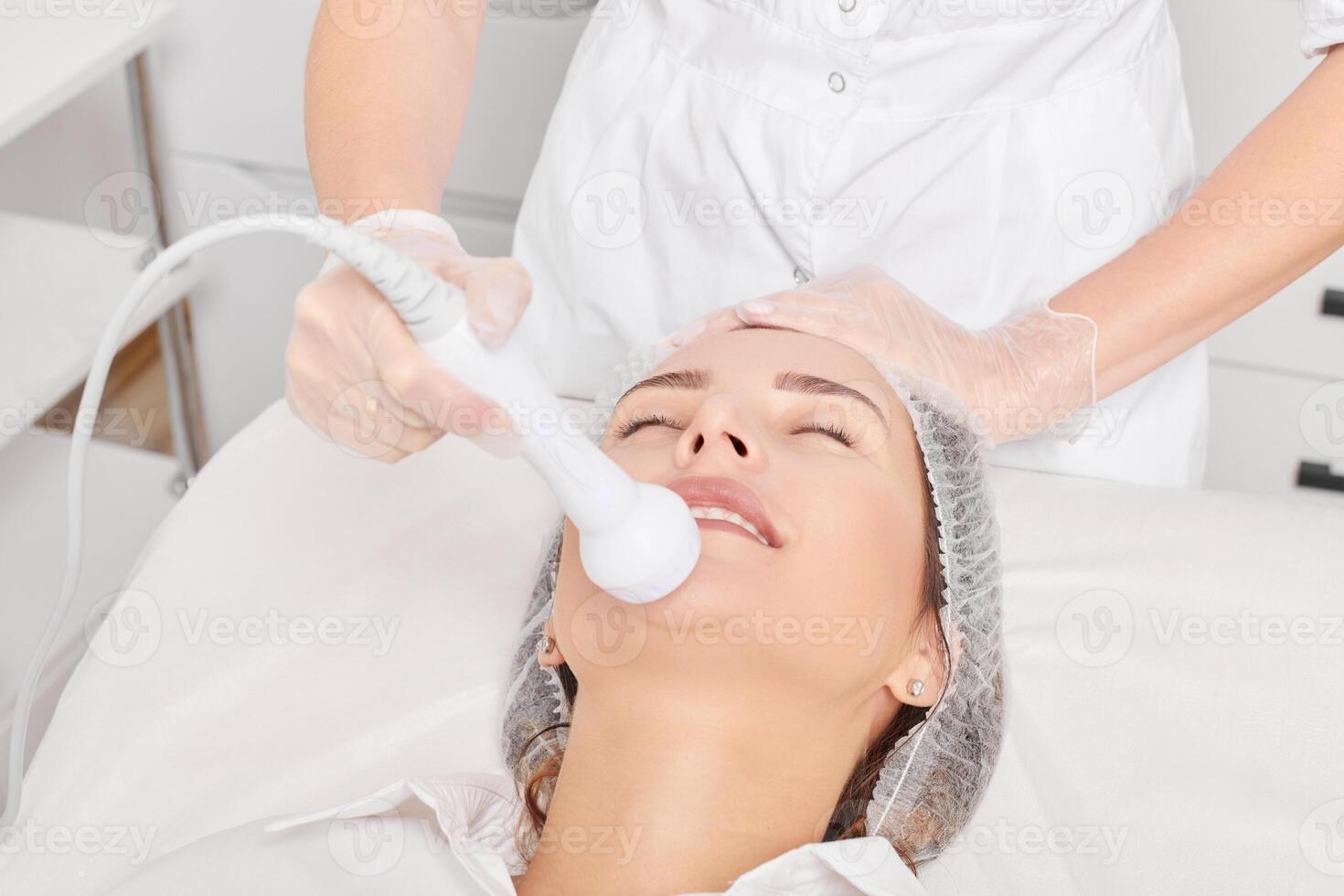 Cosmetologist makes RF lifting for rejuvenation woman face, anti aging cosmetic procedure photo