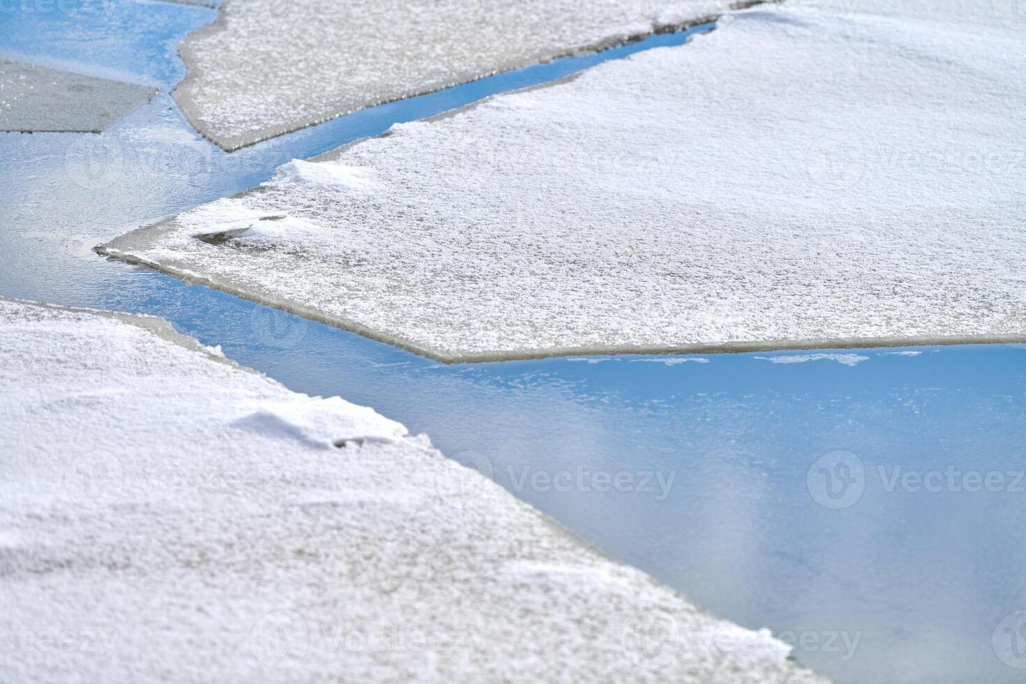 Cracked ice of frozen river, blue water, ice texture photo