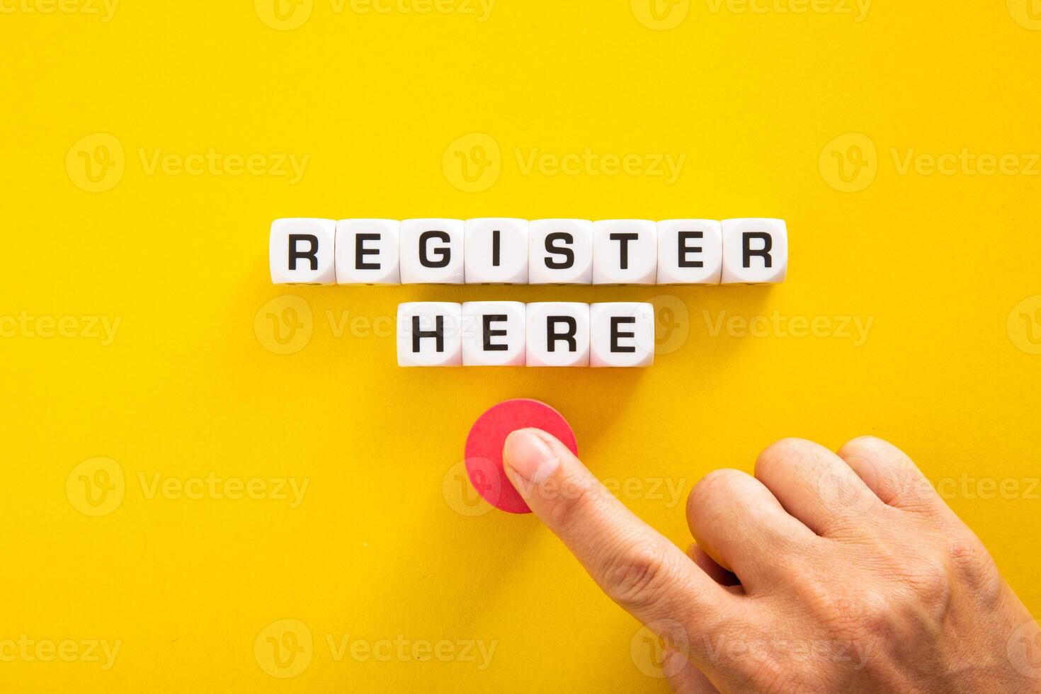Hand pushing button with Register Here word on yellow background photo