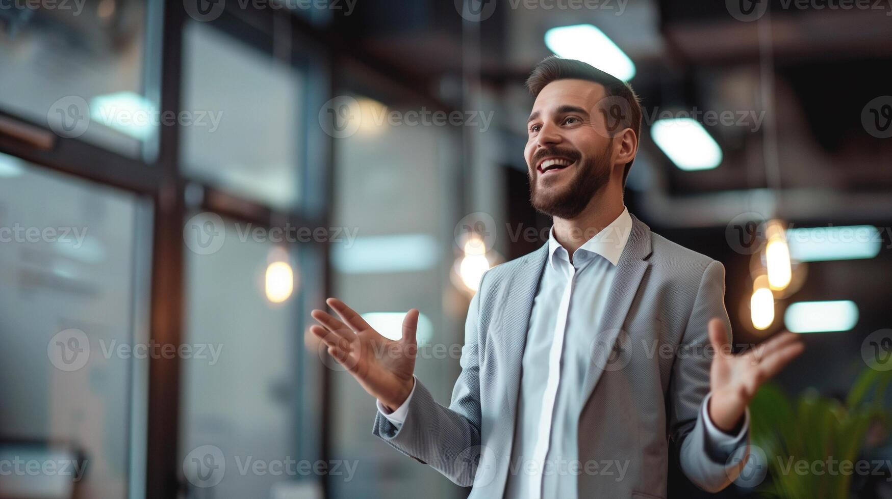 A smiling young businessman gesturing while giving a presentation in a modern office setting. photo