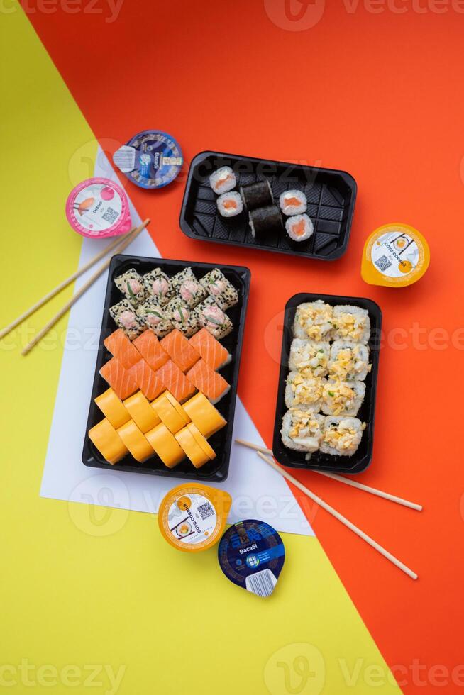 Sushi delivery. Set of rolls in a disposable box on a black background. Top view photo