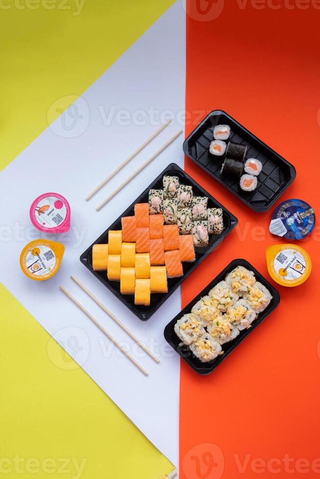 Sushi delivery. Set of rolls in a disposable box on a black background. Top view photo