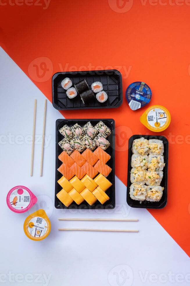 Sushi delivery. Set of rolls in a disposable box on a black background. Top view photo