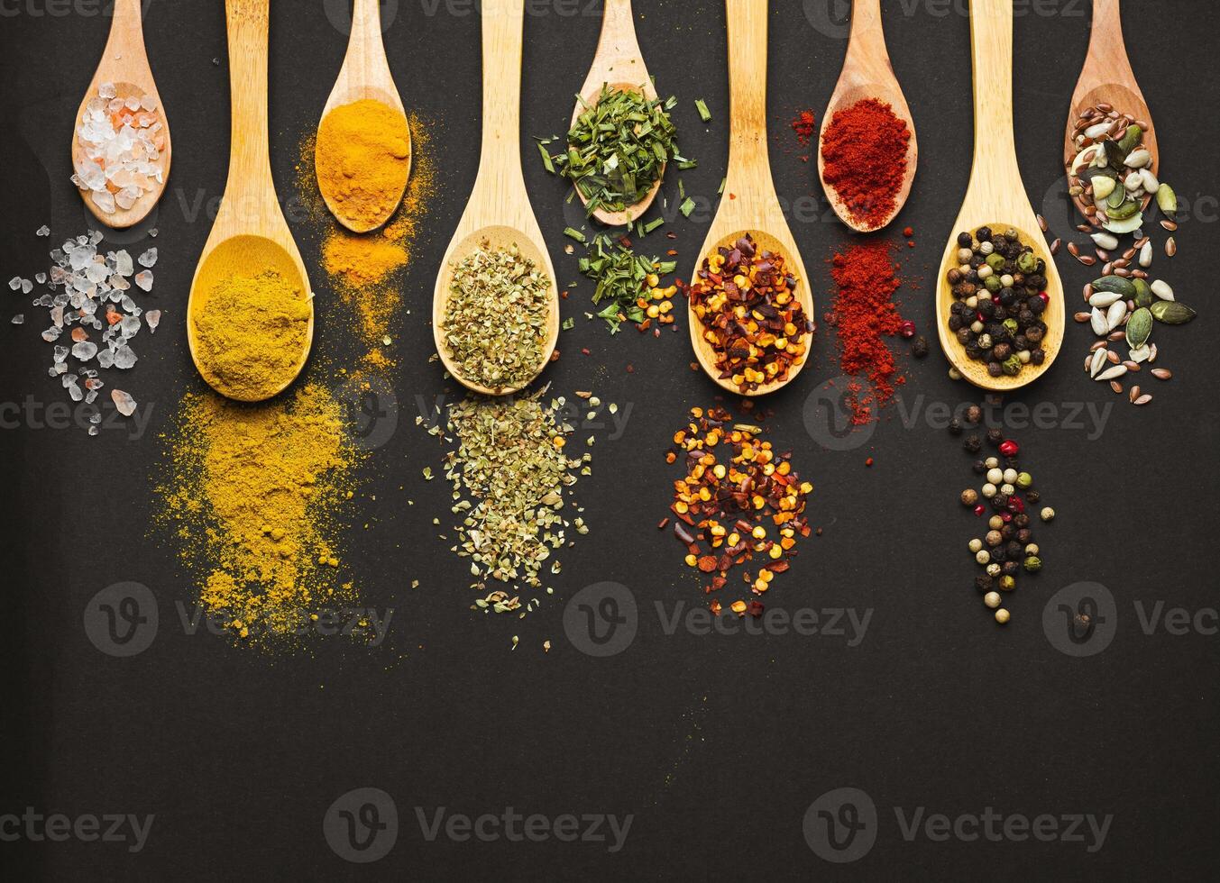 Various Asian spices in spoons on black background. Top view with free space photo