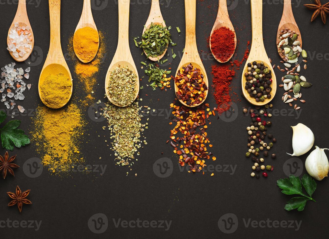 Various Asian spices in spoons on black background. Top view with free space photo