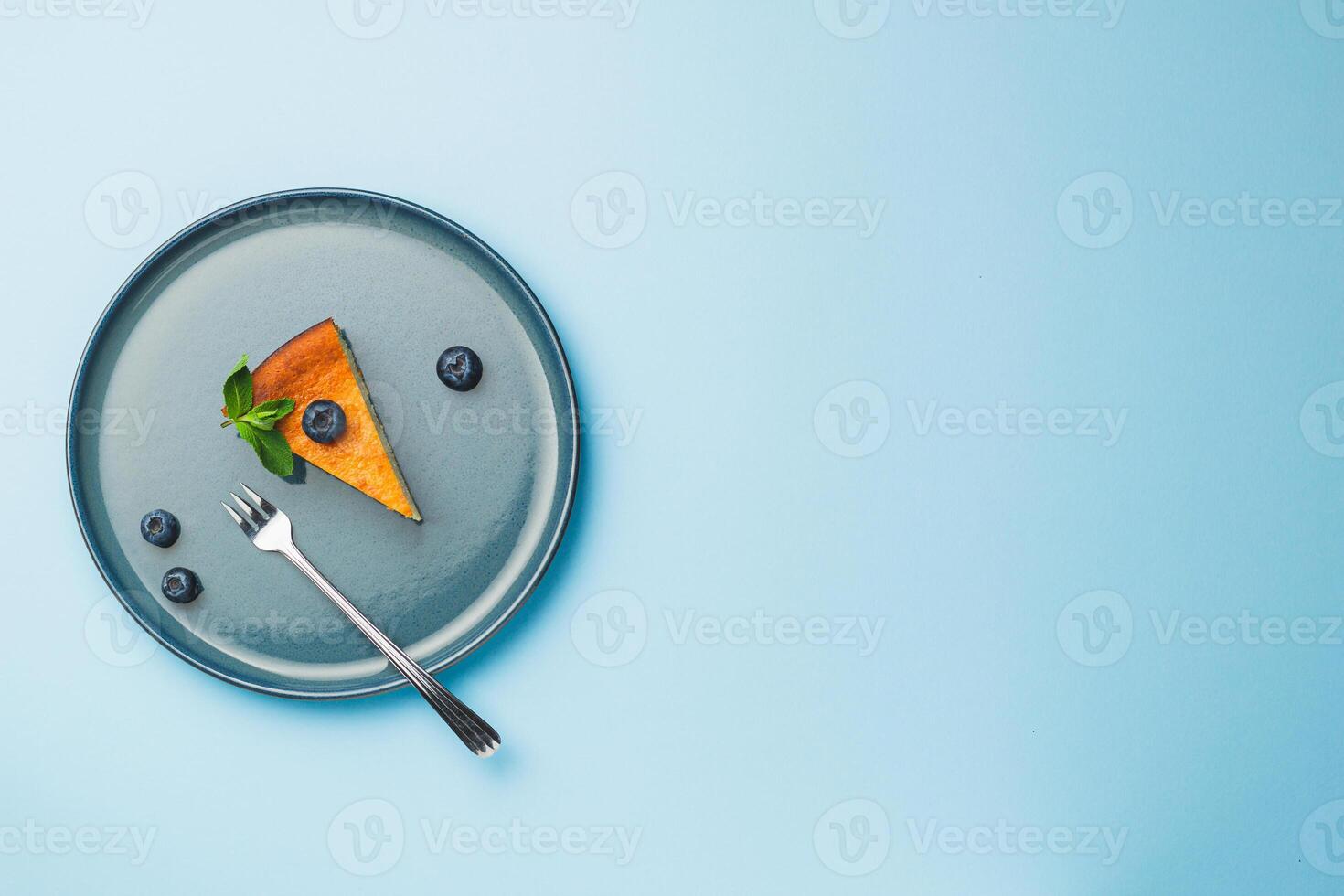 Cottage cheese cheesecake slice with fresh blueberry and mint on blue background, top view photo
