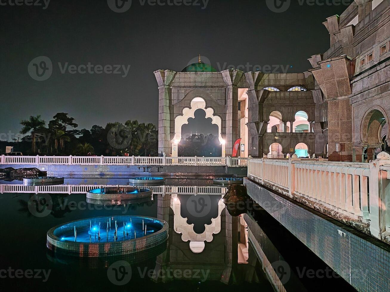 The Masjid Wilayah Persekutuan mosque in Kuala Lumpur has a beautiful pool that is particularly stunning at night due to its reflection views. photo