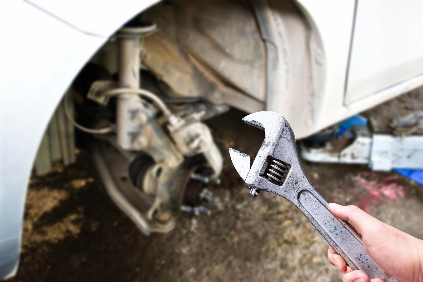 An adjustable spanner or adjustable wrench in the hand of an auto mechanic in the vehicle maintenance shop , Car maintenance service concept photo