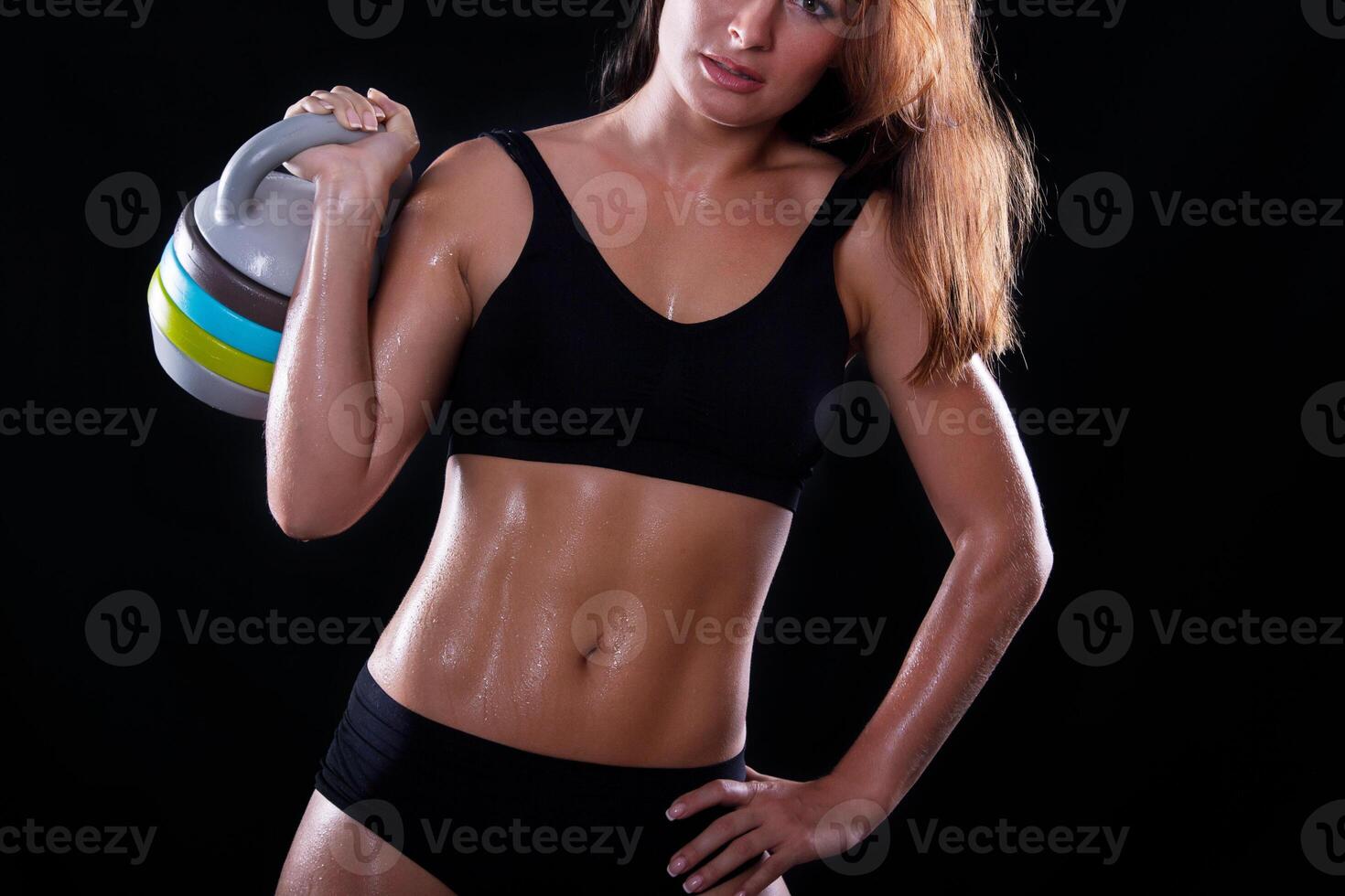Fitness girl with kettlebell on a dark background photo
