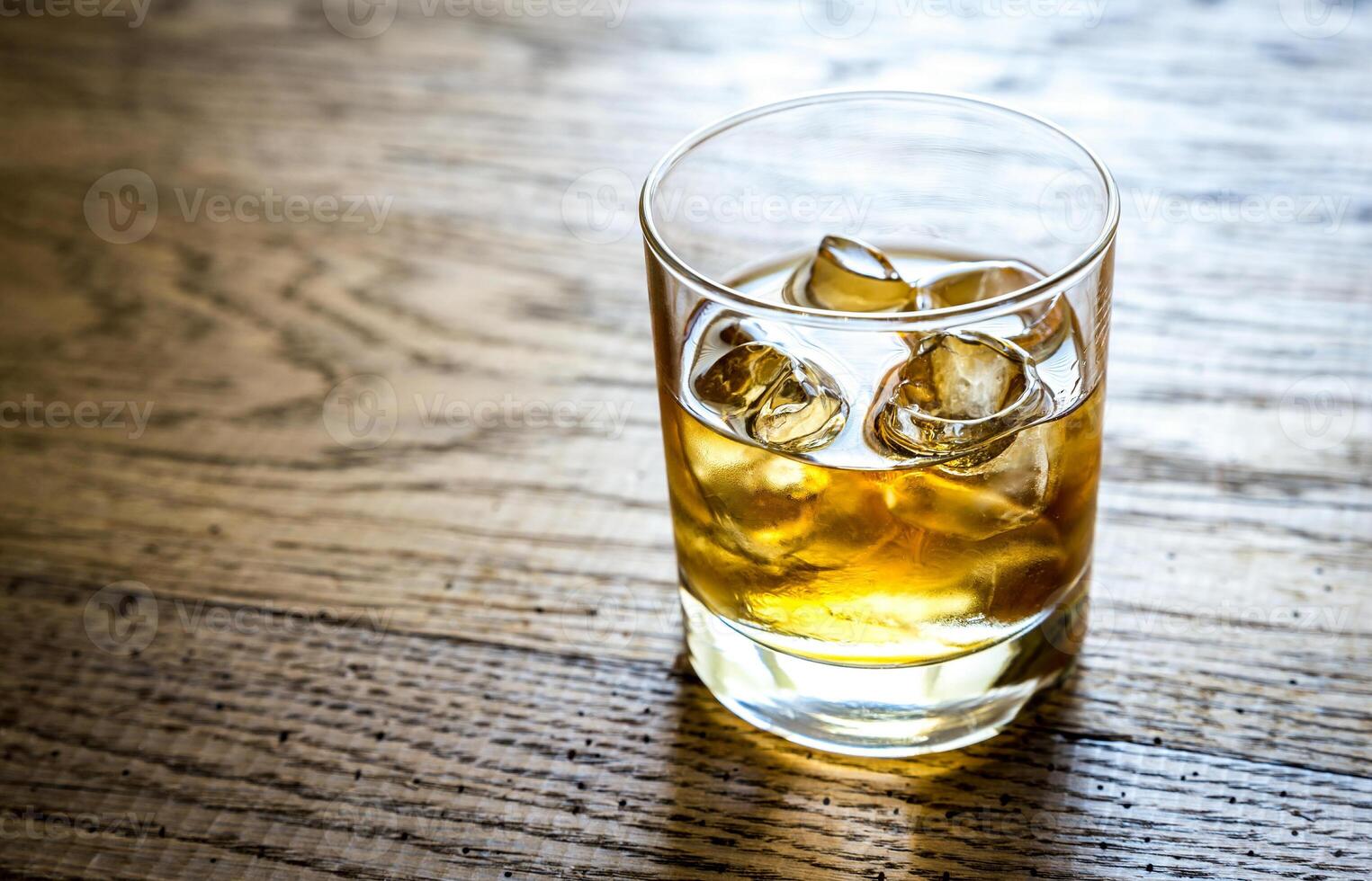 Glass of rum on the wooden background photo