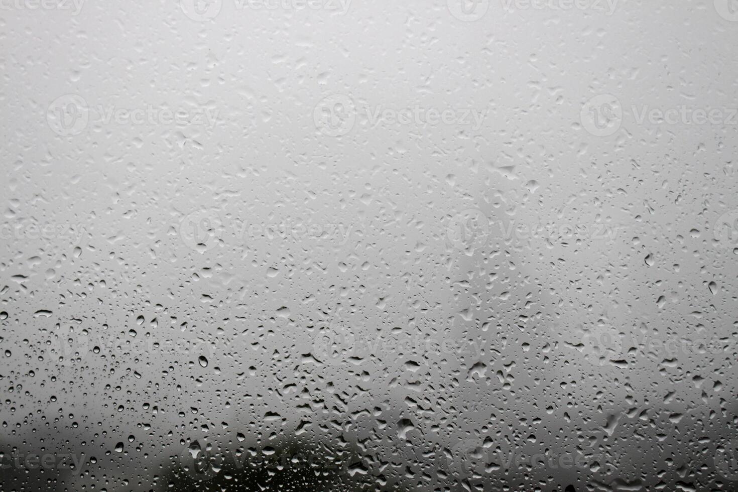 Dew drops due to rain on glass window on white fog background photo