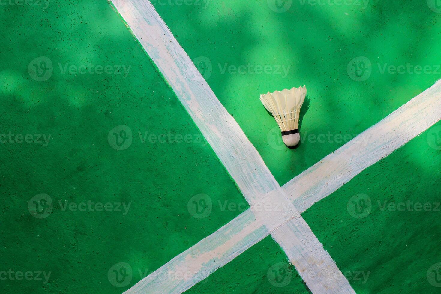 Top view, White badminton shuttlecock on green floor with crossed white stripes. photo