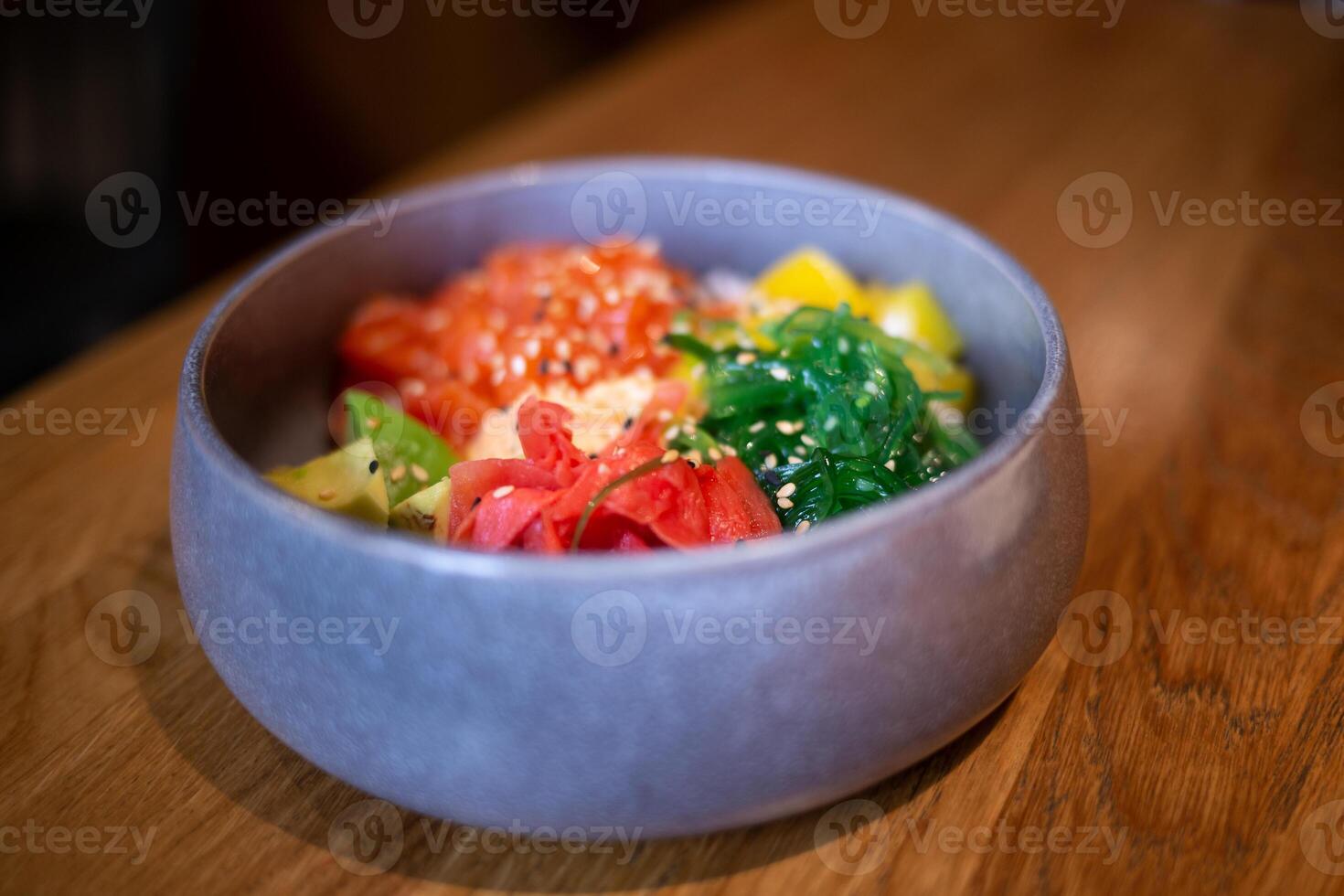Poke bowl with salmon, rice, avocado, edamame beans, cucumber and radish in a gray bowl. Hawaiian ahi poke bowl, gray background photo