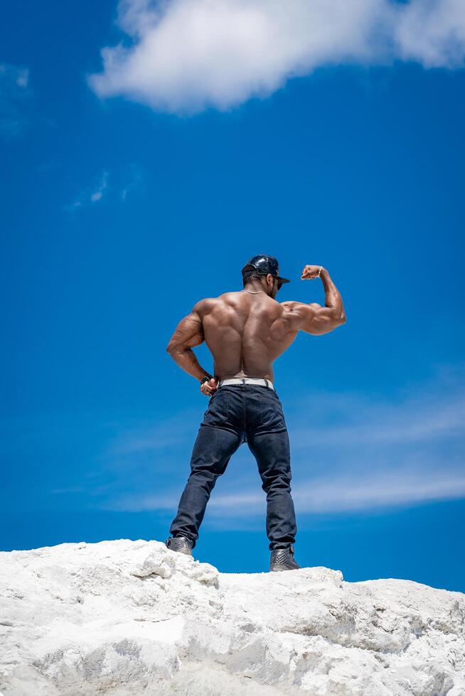 Strong shirtless male model posing outdoor. Athletic attractive young bodybuilder. photo