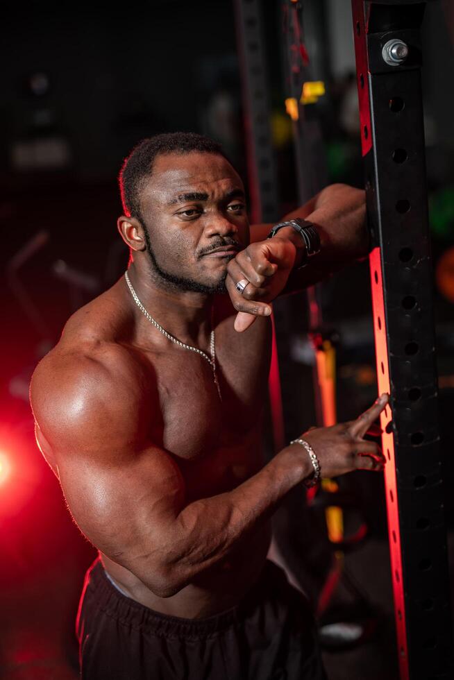 Bodybuilder leaned at sport equioment and poses without t-shirt in thoughtful mood. Handsome and muscular athlete. photo