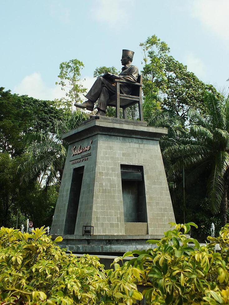 Surakarta, Central Java, Indonesia April 11, 2024. The statue of Mr Soekarno sitting while reading a book, statue of the first president of The Republik Indonesia at Manahan Stadium. photo