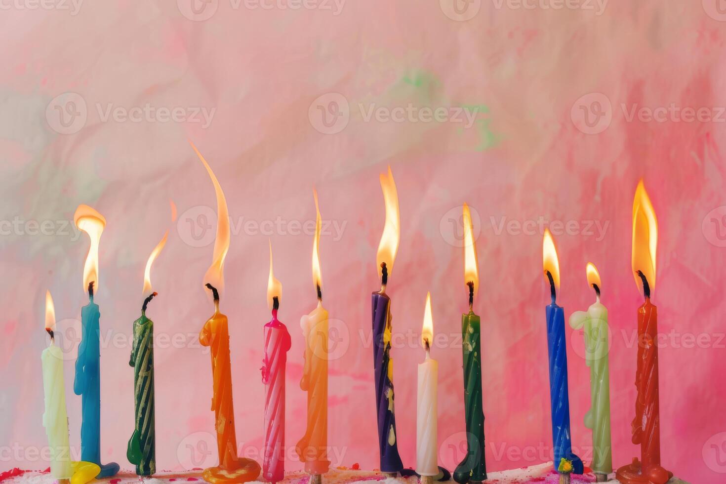 A row of candles with different colors and sizes, some of which are lit photo