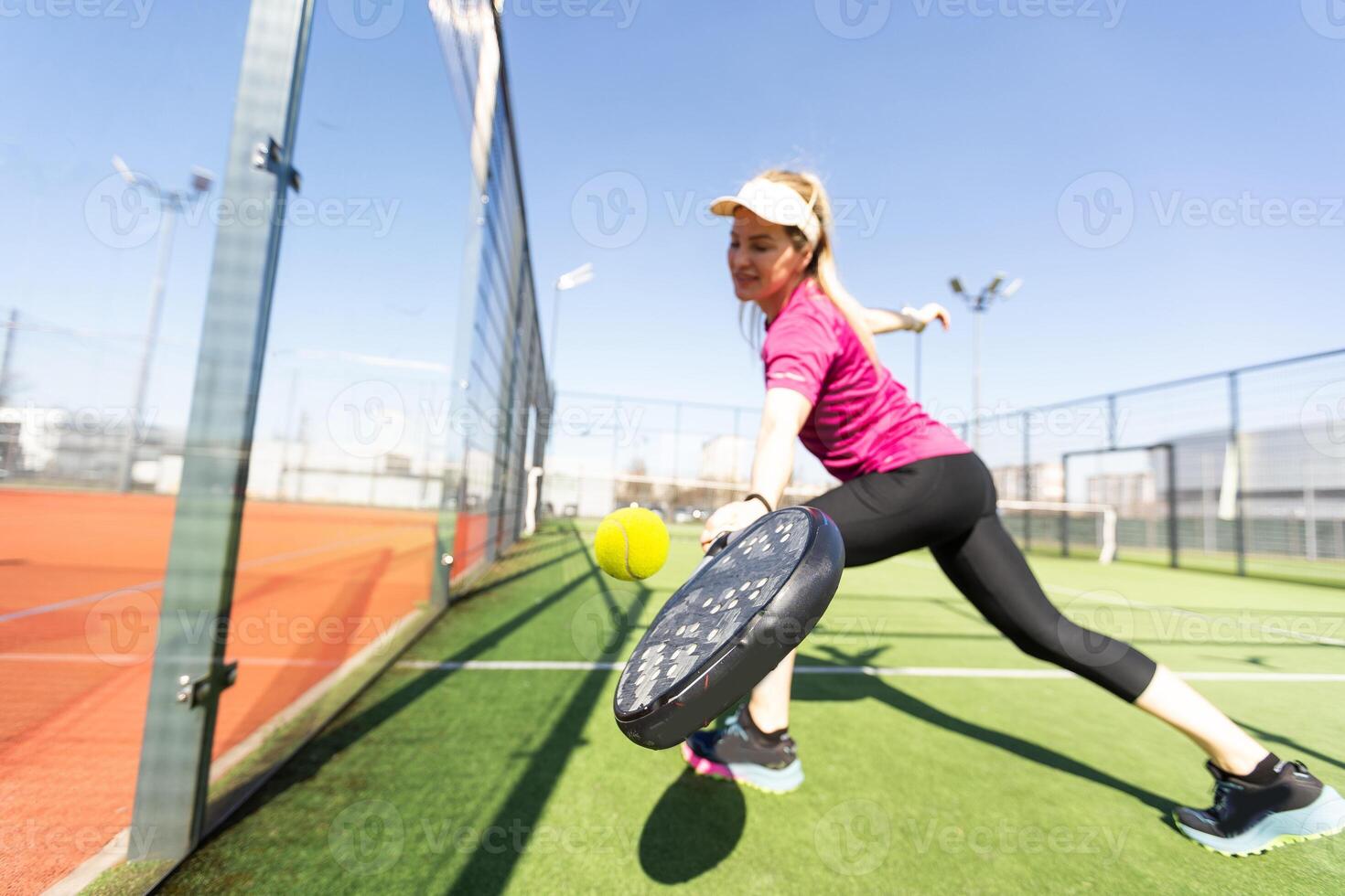 Active young woman trying to beat the ball by Padel racket while playing tennis in the court photo