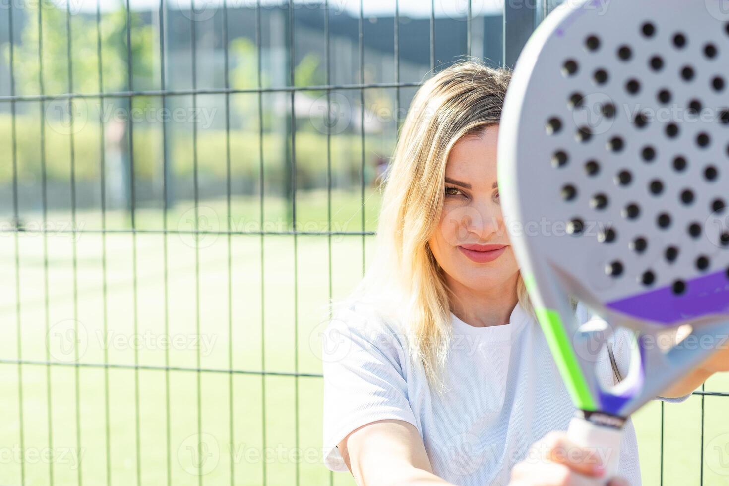 Happy female paddle tennis player during practice on outdoor court looking at camera. Copy space. photo