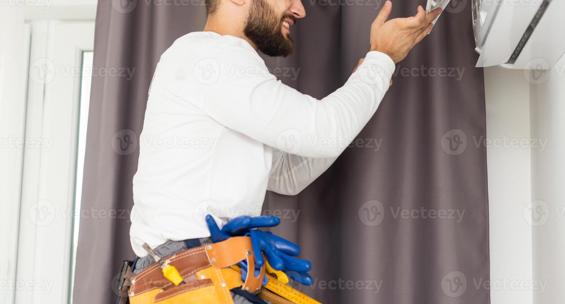 Male technician repairing air conditioner indoors photo