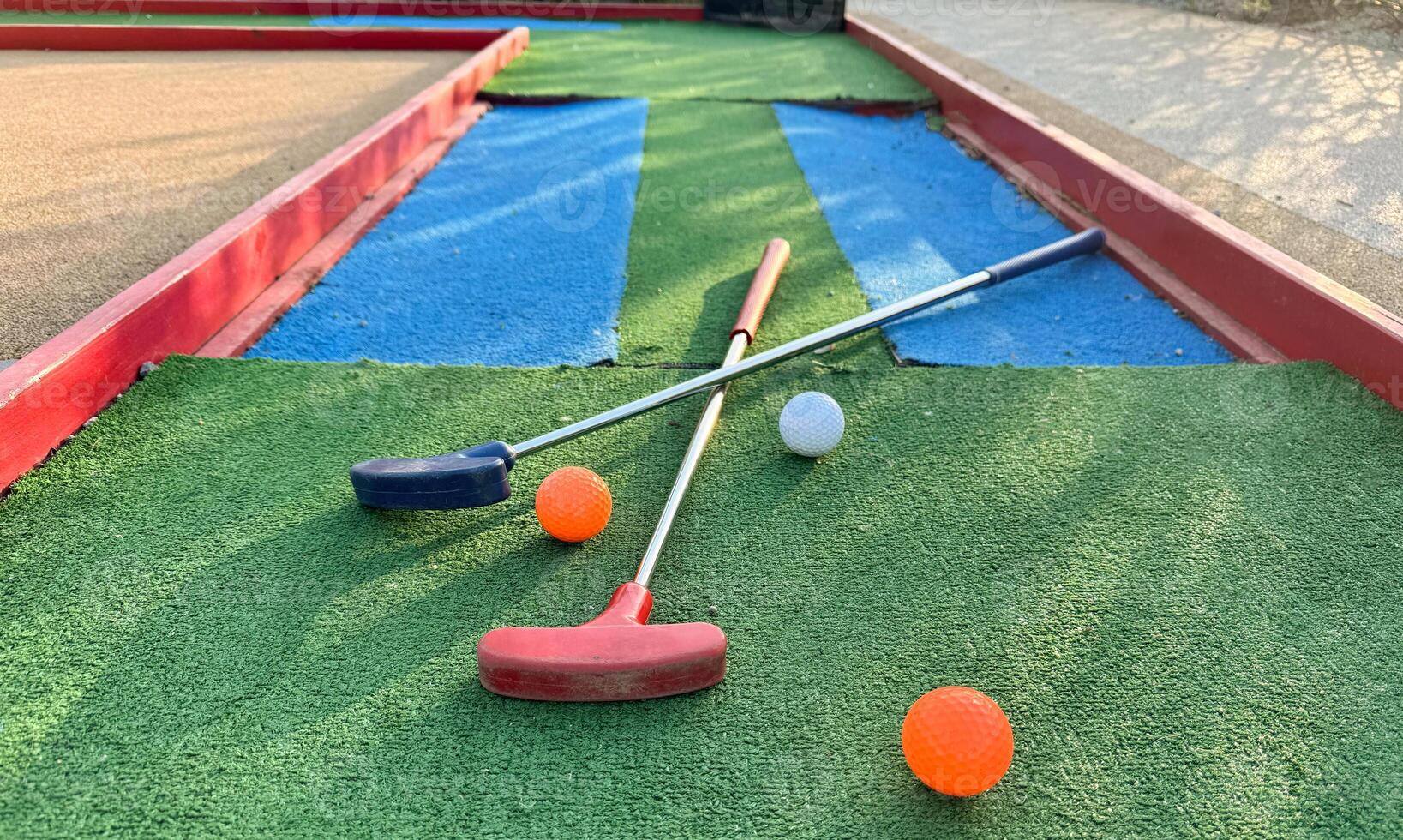 colorful golf putters with golf balls on synthetic grass photo