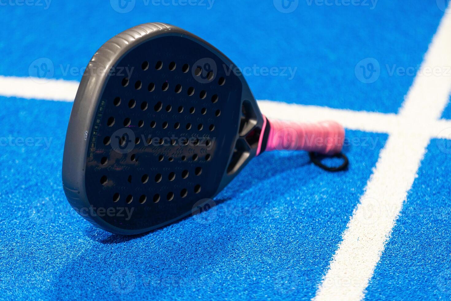 Black professional paddle tennis racket and ball with natural lighting on blue background. Horizontal sport theme poster, greeting cards, headers, website and app photo