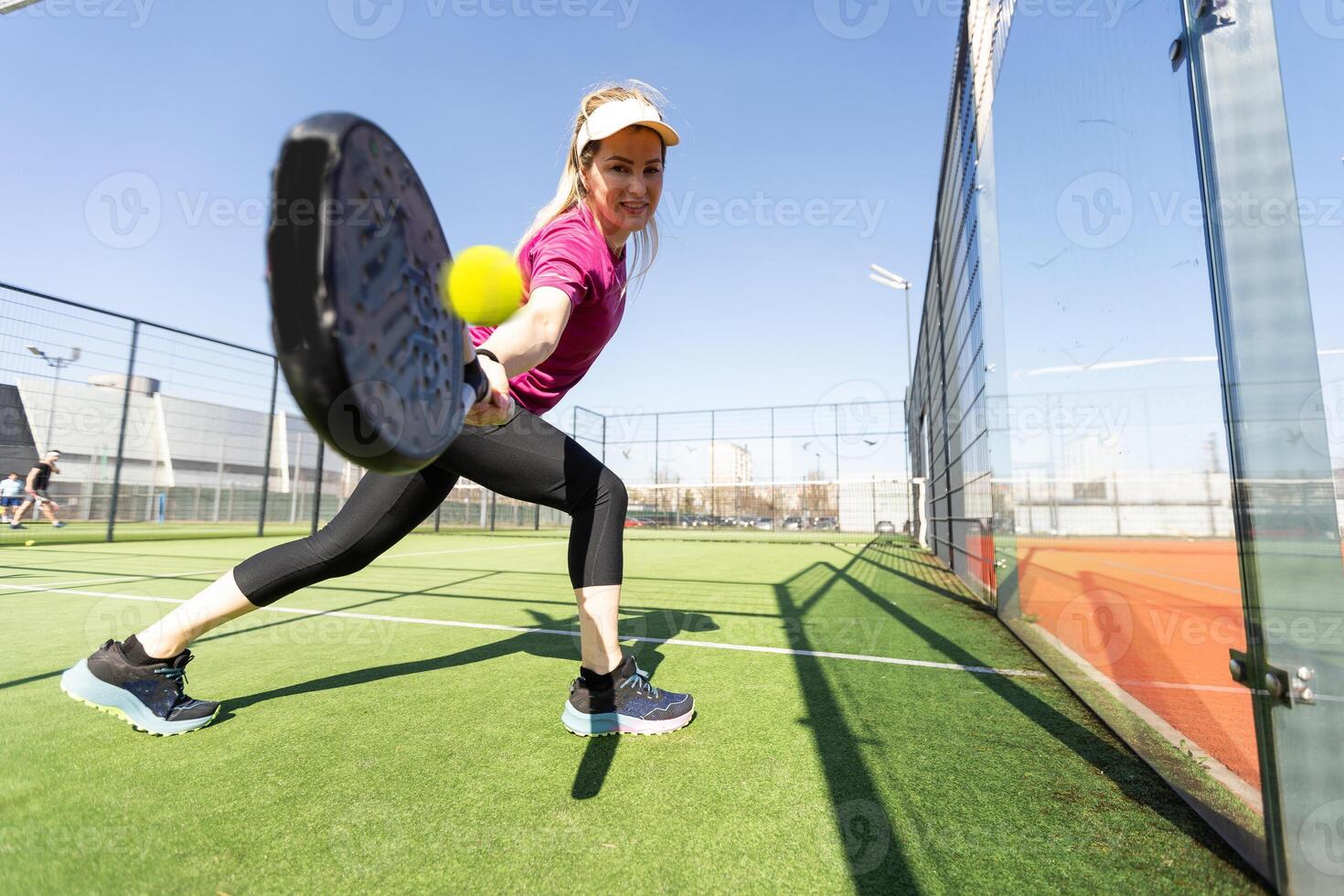 Sportive young girl with racquet playing padel in the open court outdoors photo