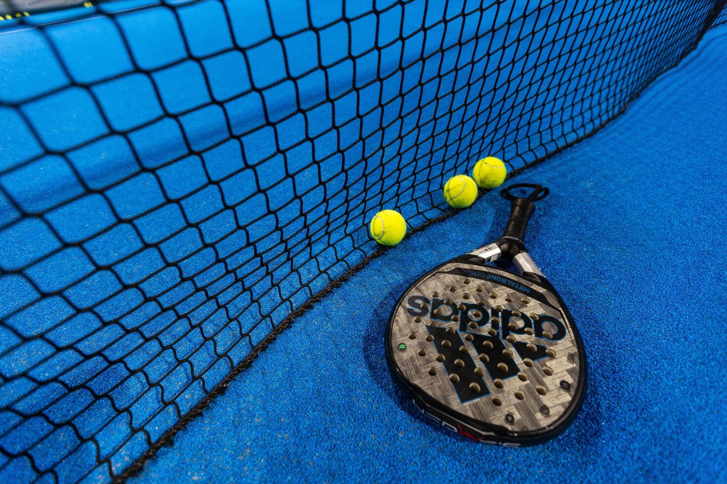 Kyiv, Ukraine, April 18, 2024. Black professional paddle tennis racket and ball with natural lighting on blue background. Horizontal sport theme poster, greeting cards, headers, website and app photo