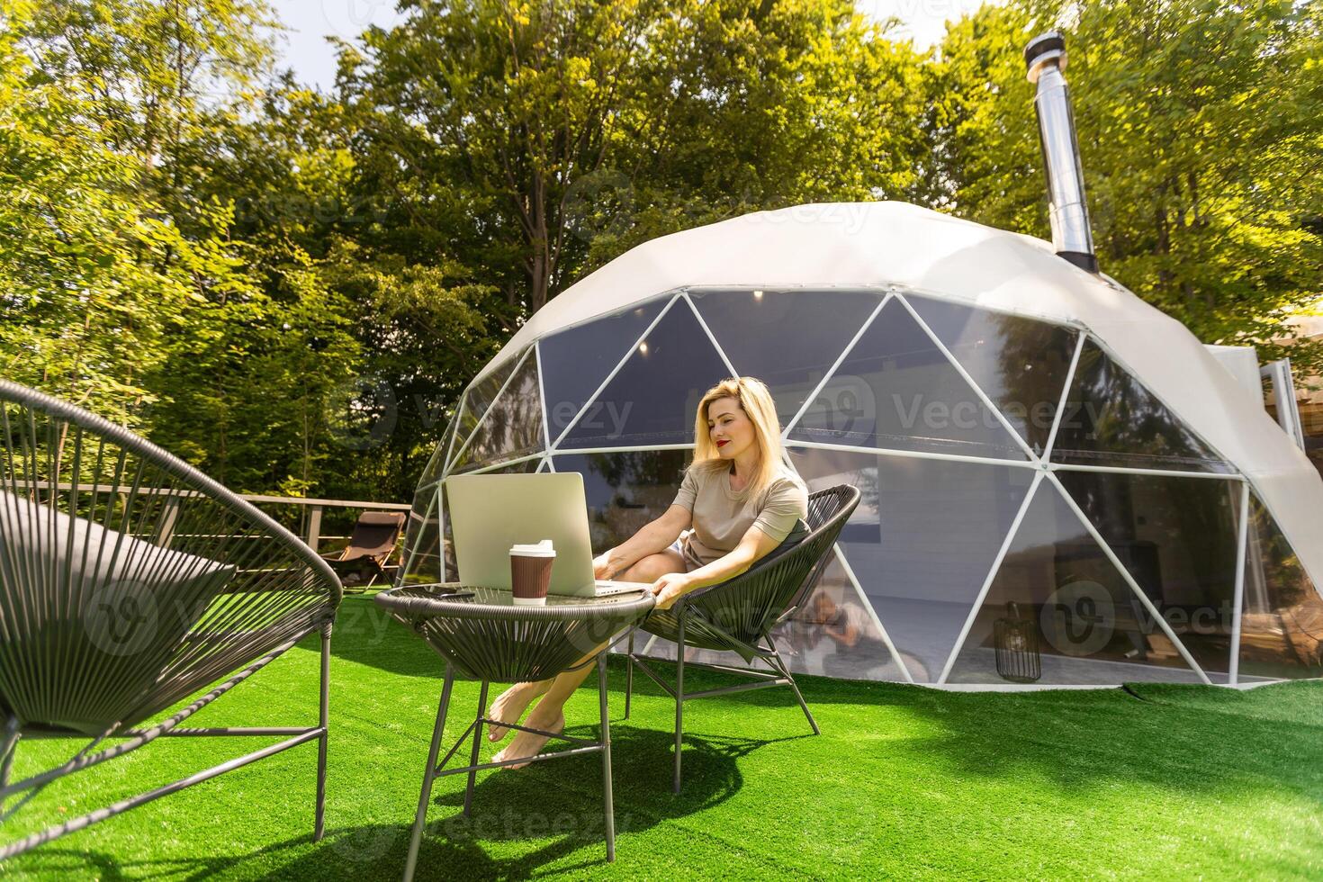 middle aged woman uses a laptop resting and spending time at Glamping house on holidays. holiday dome tent. Cozy, camping, hygge, lifestyle concept photo