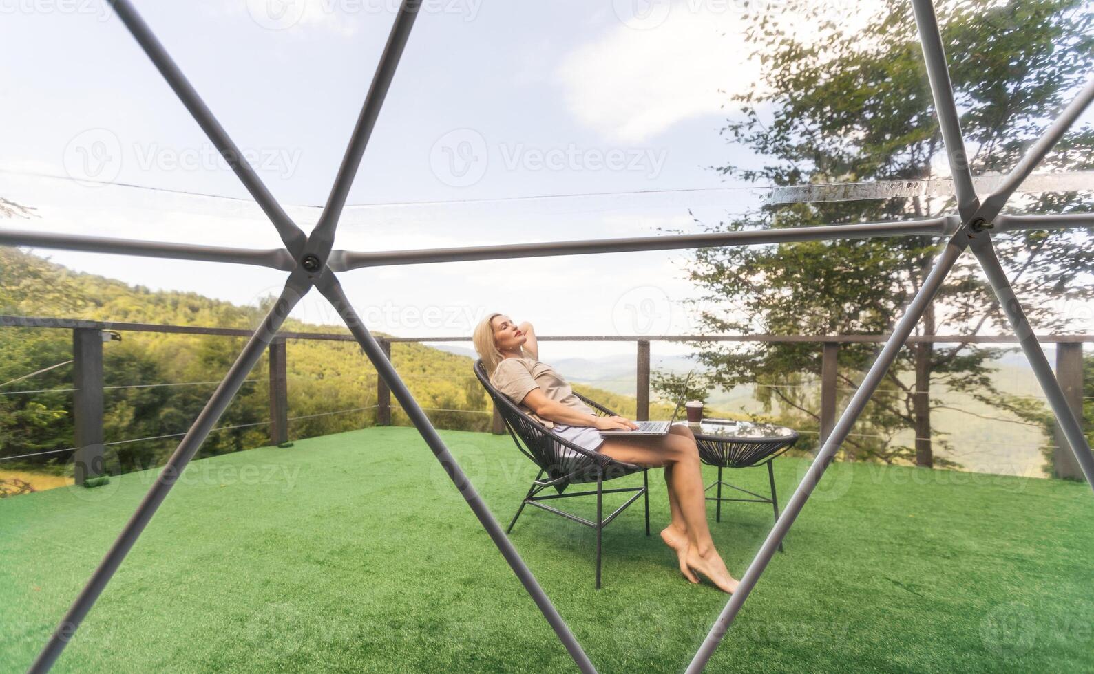middle aged woman uses a laptop resting and spending time at Glamping house on holidays. holiday dome tent. Cozy, camping, hygge, lifestyle concept photo
