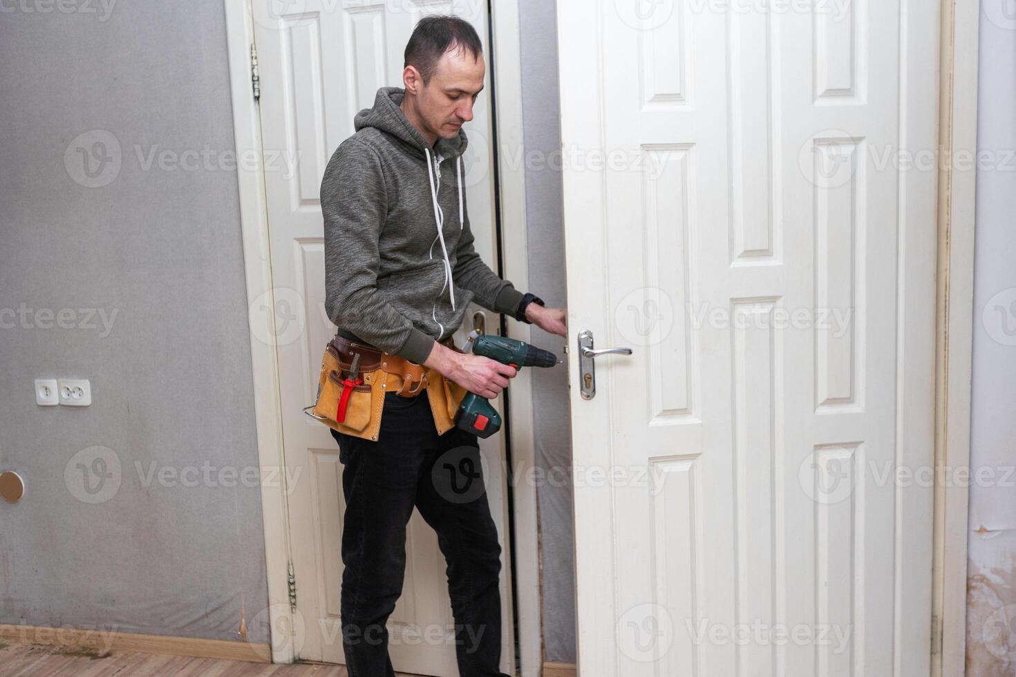 Locksmith, man and maintenance, handyman with home renovation and fixing, change door locks with power tools. Construction, building industry and trade with manual labour, vocation and employee photo