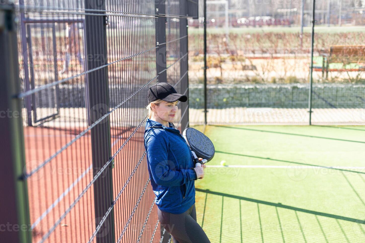 One woman with racquet and ball behind the net in paddle tennis court ready for training photo