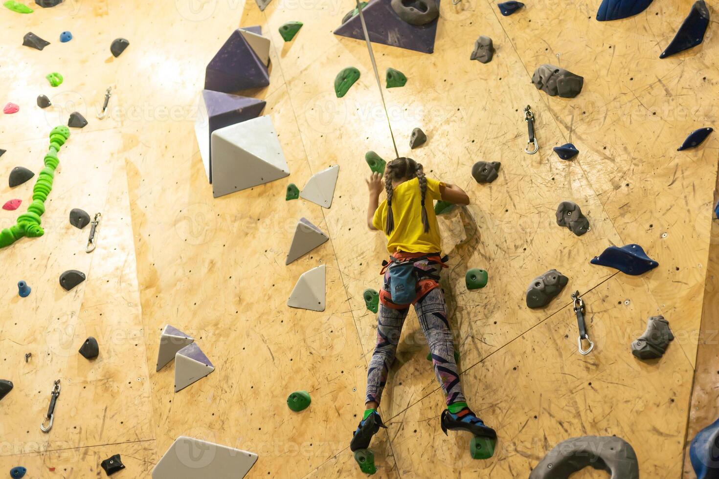 bouldering, little girl climbing up the wall photo
