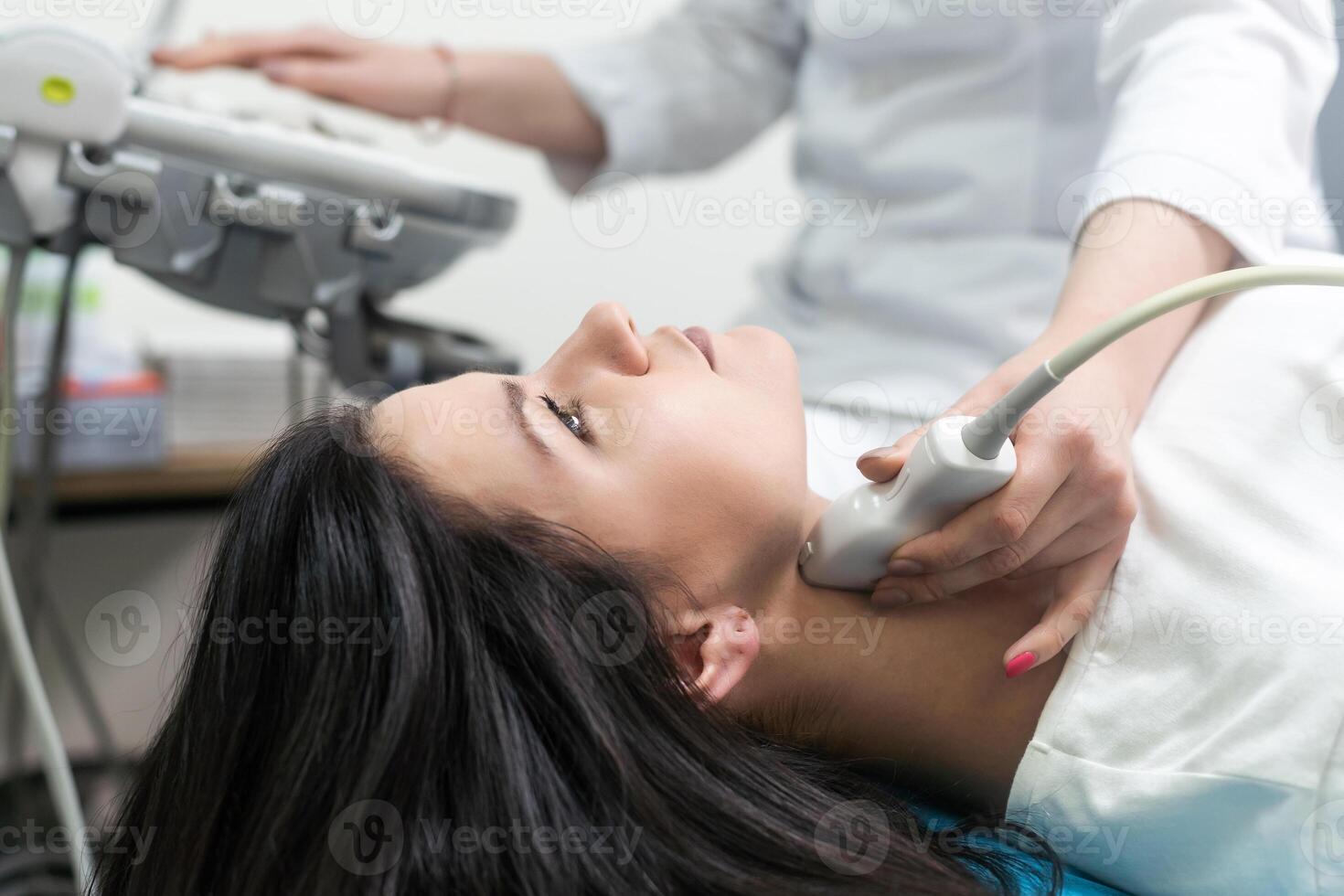 Doctor using ultrasound scanning machine for examining a thyroid of woman. photo