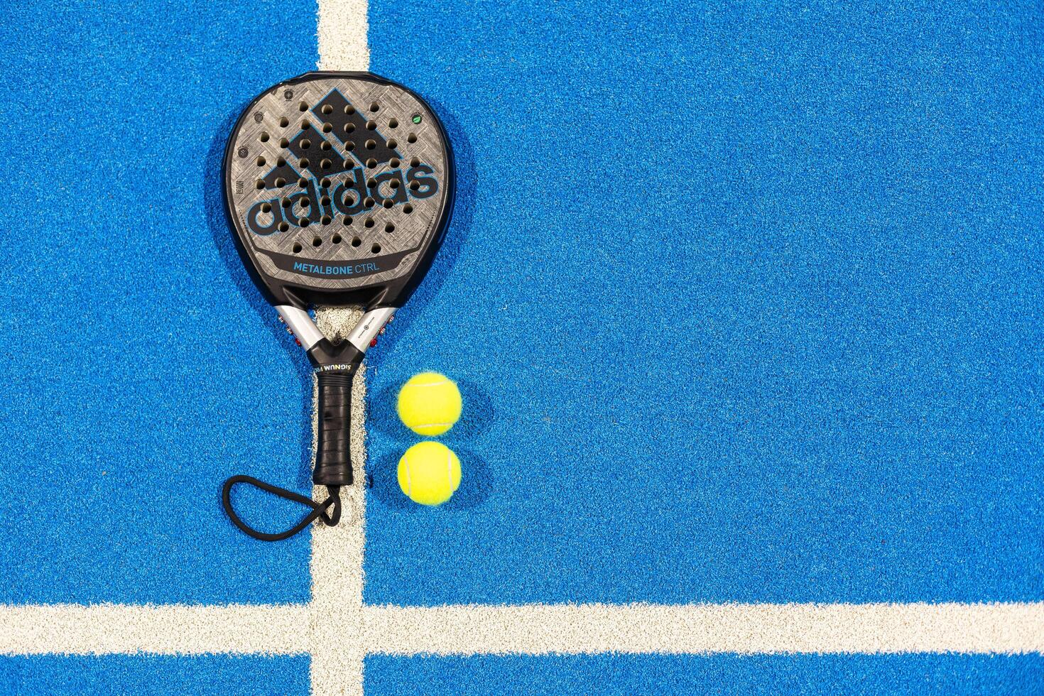 Kyiv, Ukraine, April 18, 2024. Black professional paddle tennis racket and ball with natural lighting on blue background. Horizontal sport theme poster, greeting cards, headers, website and app photo