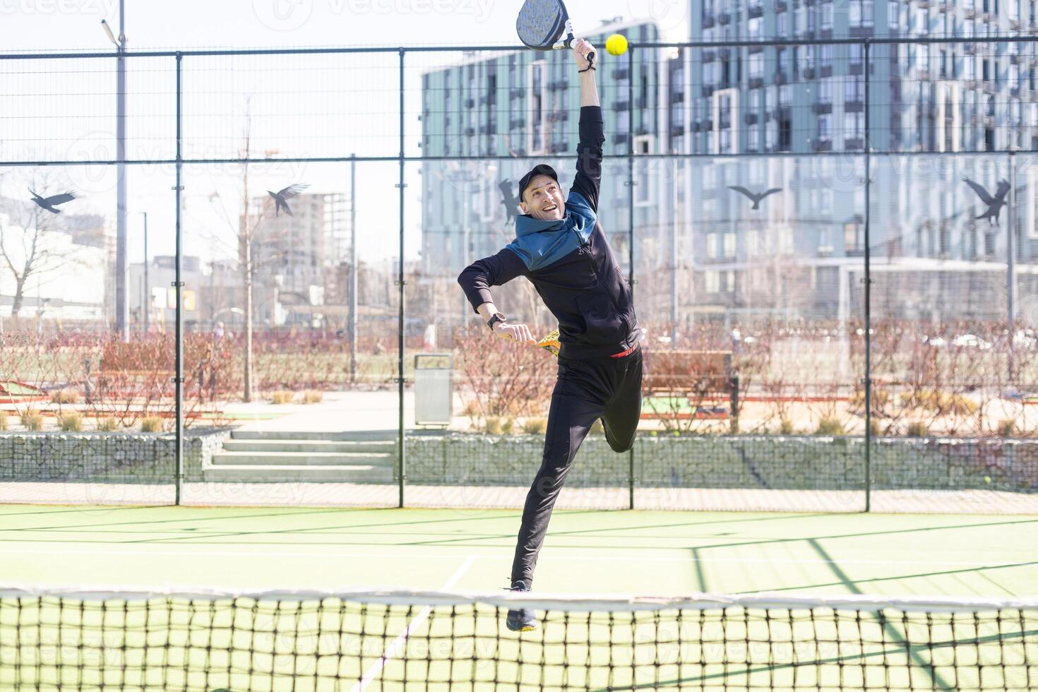 Man playing padel in a green grass padel court indoor behind the net photo