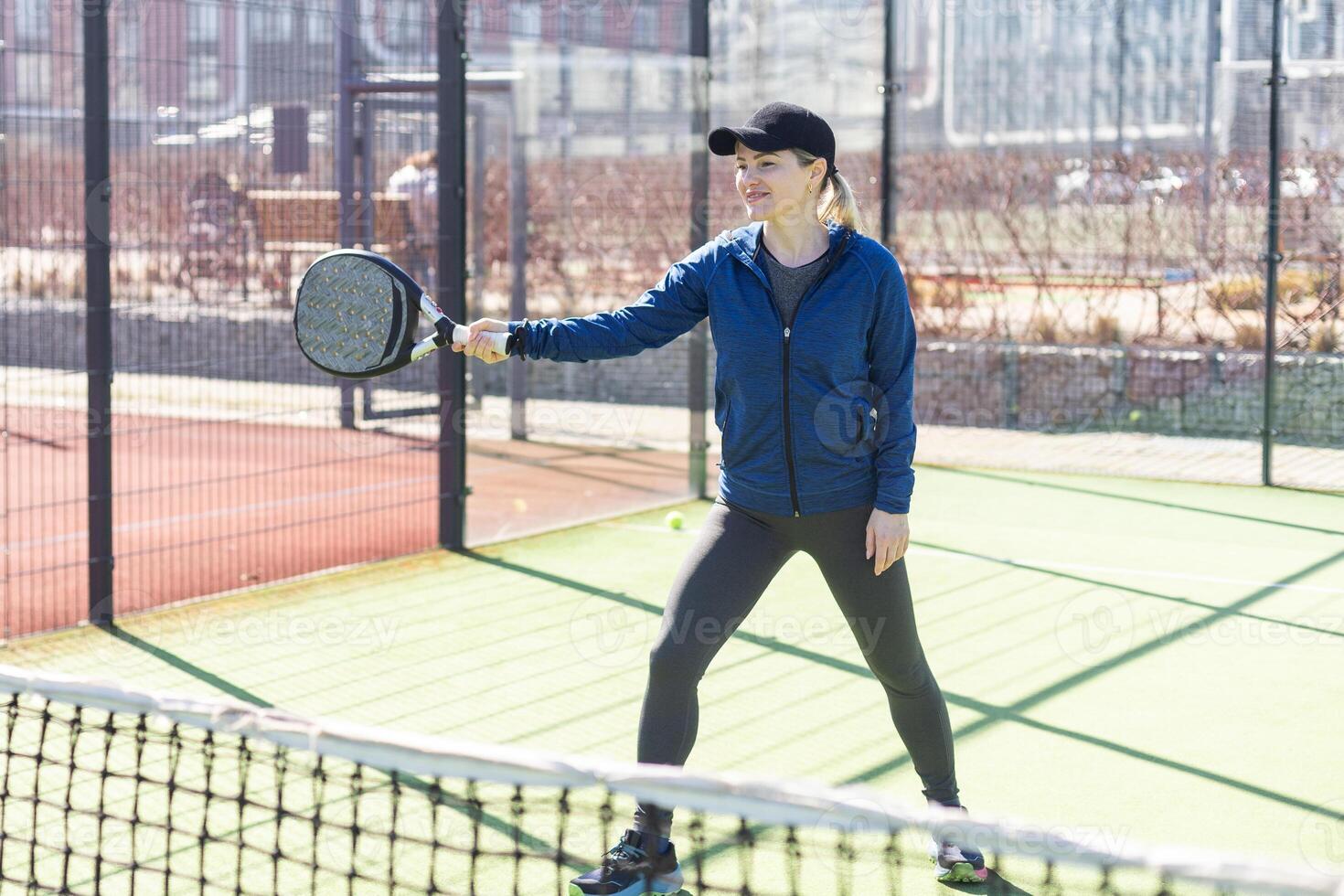 Determined sporty young woman playing padel in court photo