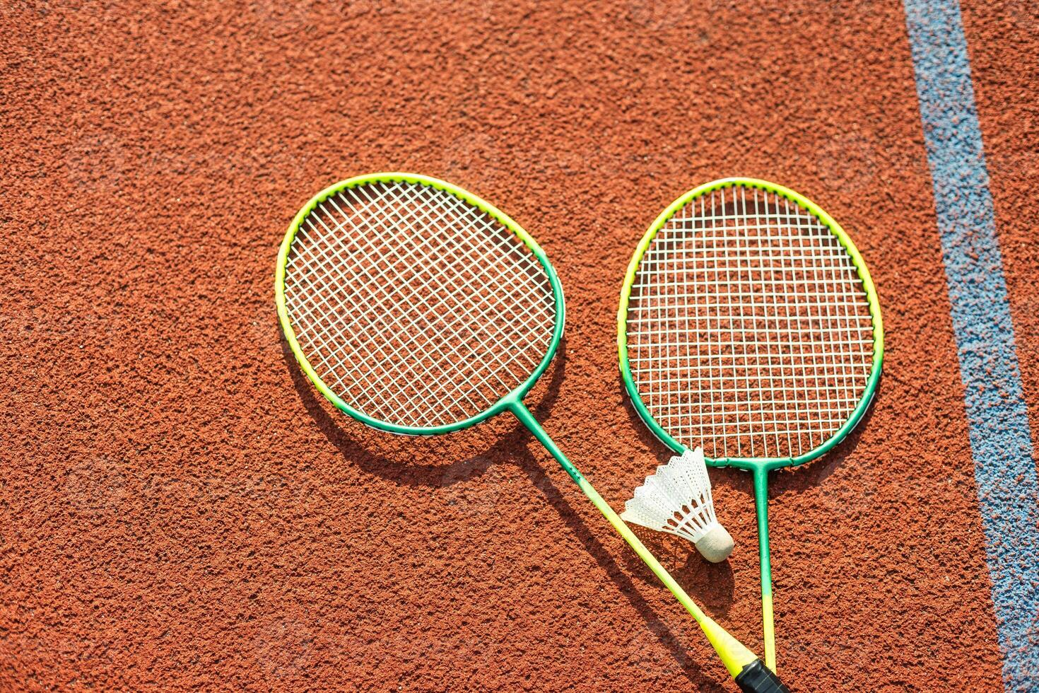 Badminton shuttlecocks and racket, placed in the corner of a synthetic field. photo