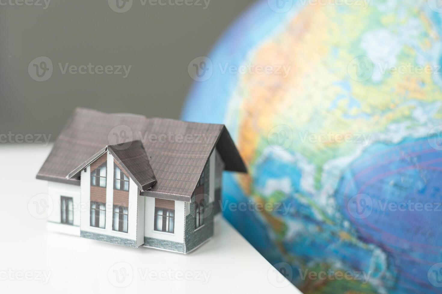 House miniature with globe in background against plain wall photo