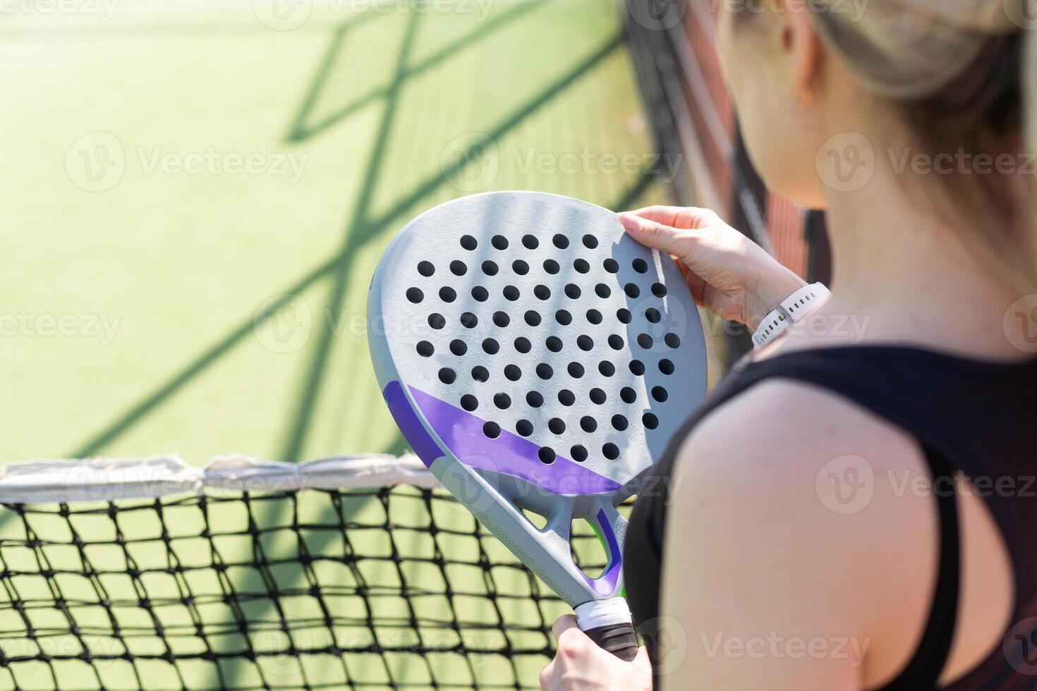 hands of a woman paddle player is holding balls and the racket at the background at the beginning of the match outdoors photo
