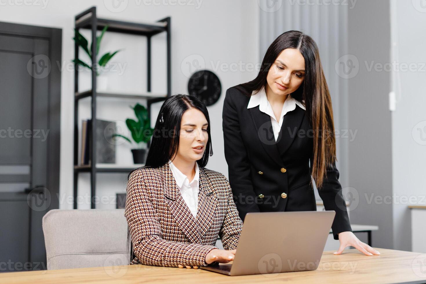 Call center agent with headset working on support hotline in modern office. Two young attractive women are working in the office photo