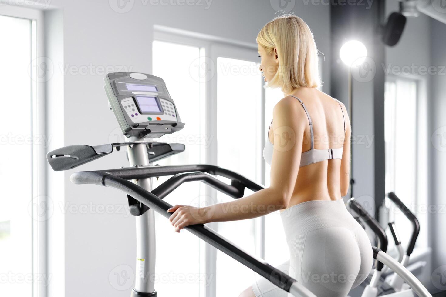 Young woman in sportswear working out at the gym. She is working out on stairway simulator photo
