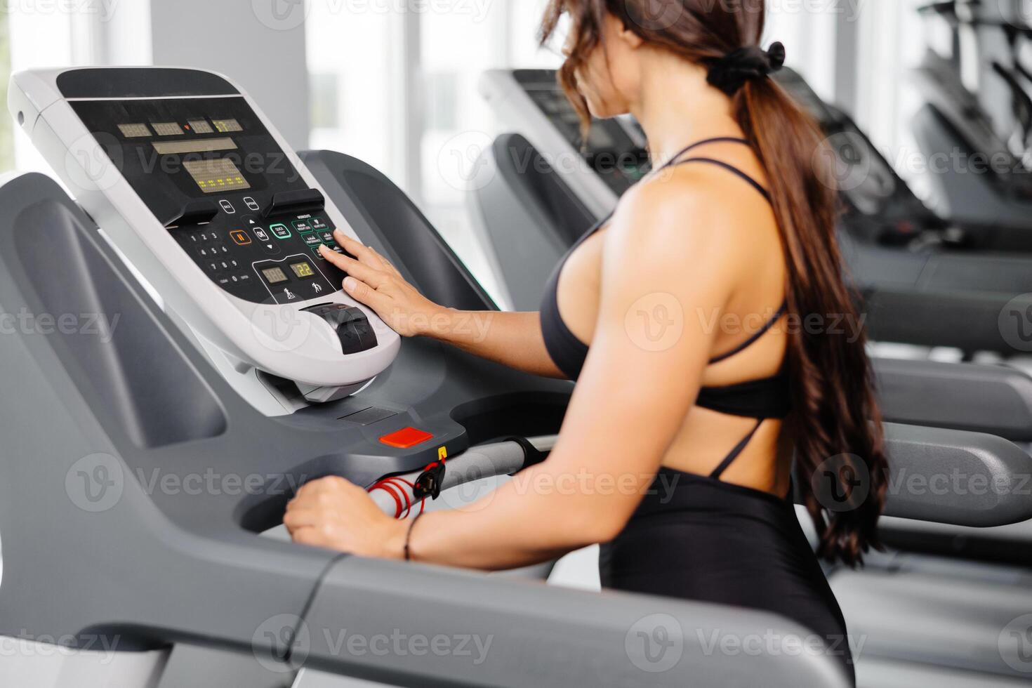 Attractive young sports woman is working out in gym, she doing cardio training on treadmill. Running on treadmill. photo